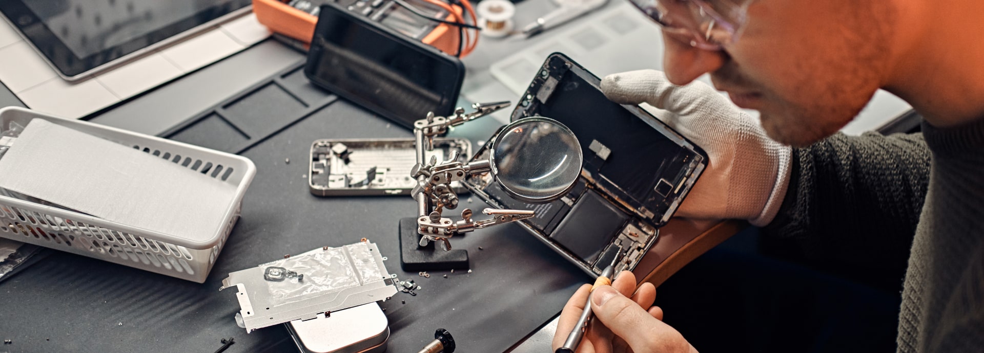 Technician repairing a disassembled phone on the bench at Phone Addicts in San Antonio